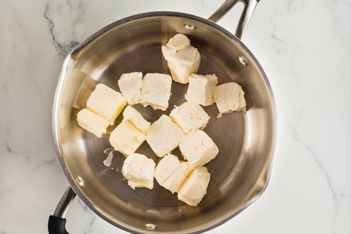 Cubed cream cheese and butter pieces in a stainless steel saucepan.