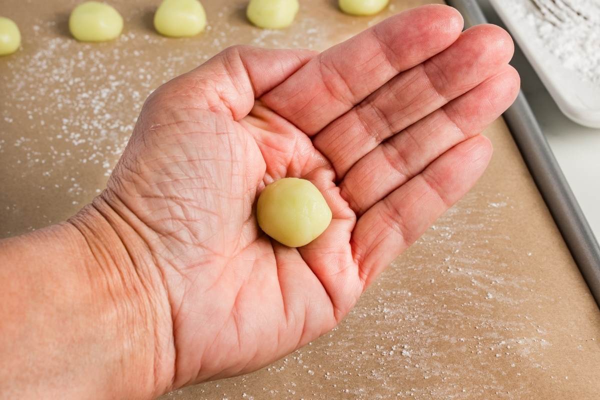 A hand holding a small round ball of mint dough.