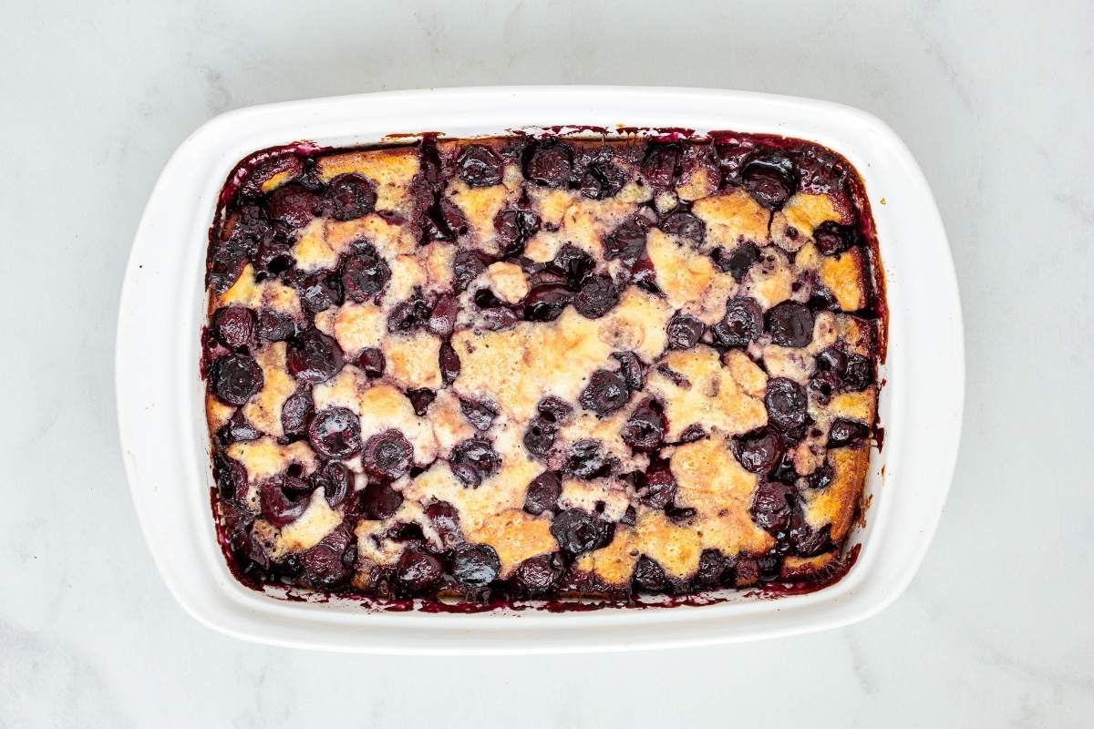 Overhead view of a baked cherry cobbler in a white rectangular baking dish.