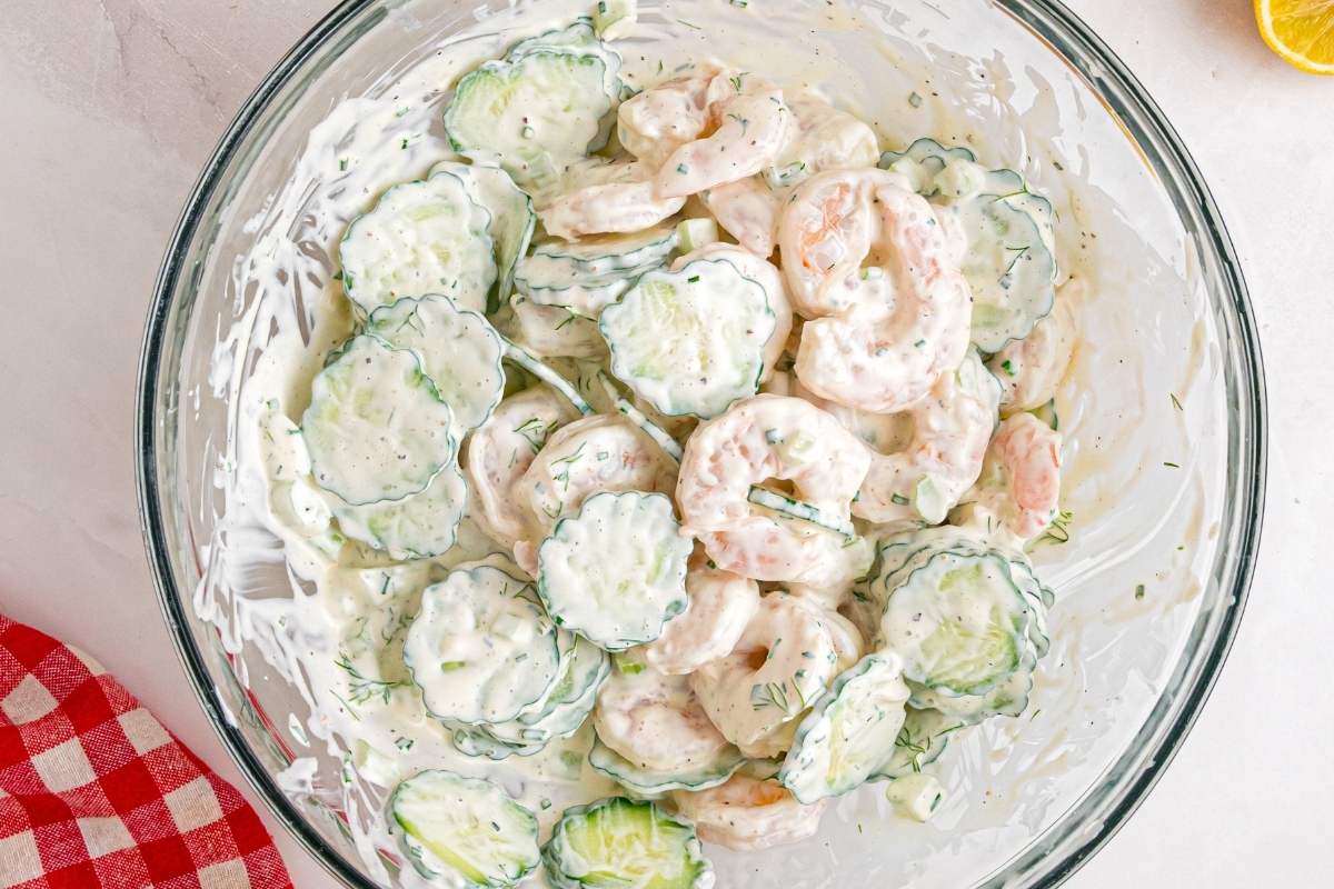Creamy shrimp and cucumber salad in a large glass mixing bowl.