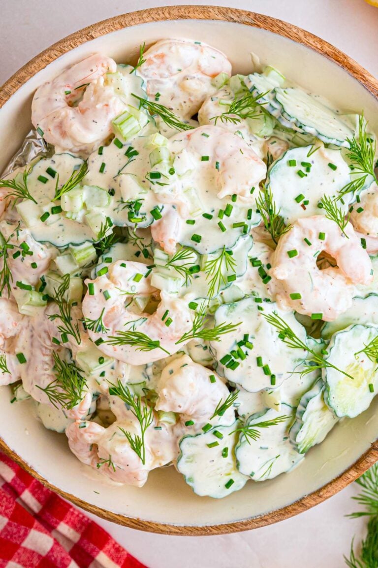 Close up of creamy shrimp and sliced cucumber salad in a wooden bowl.