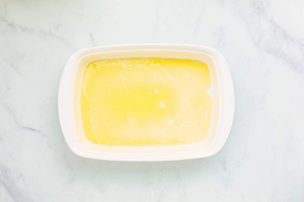 Melted butter coating the bottom of a white rectangular baking dish.