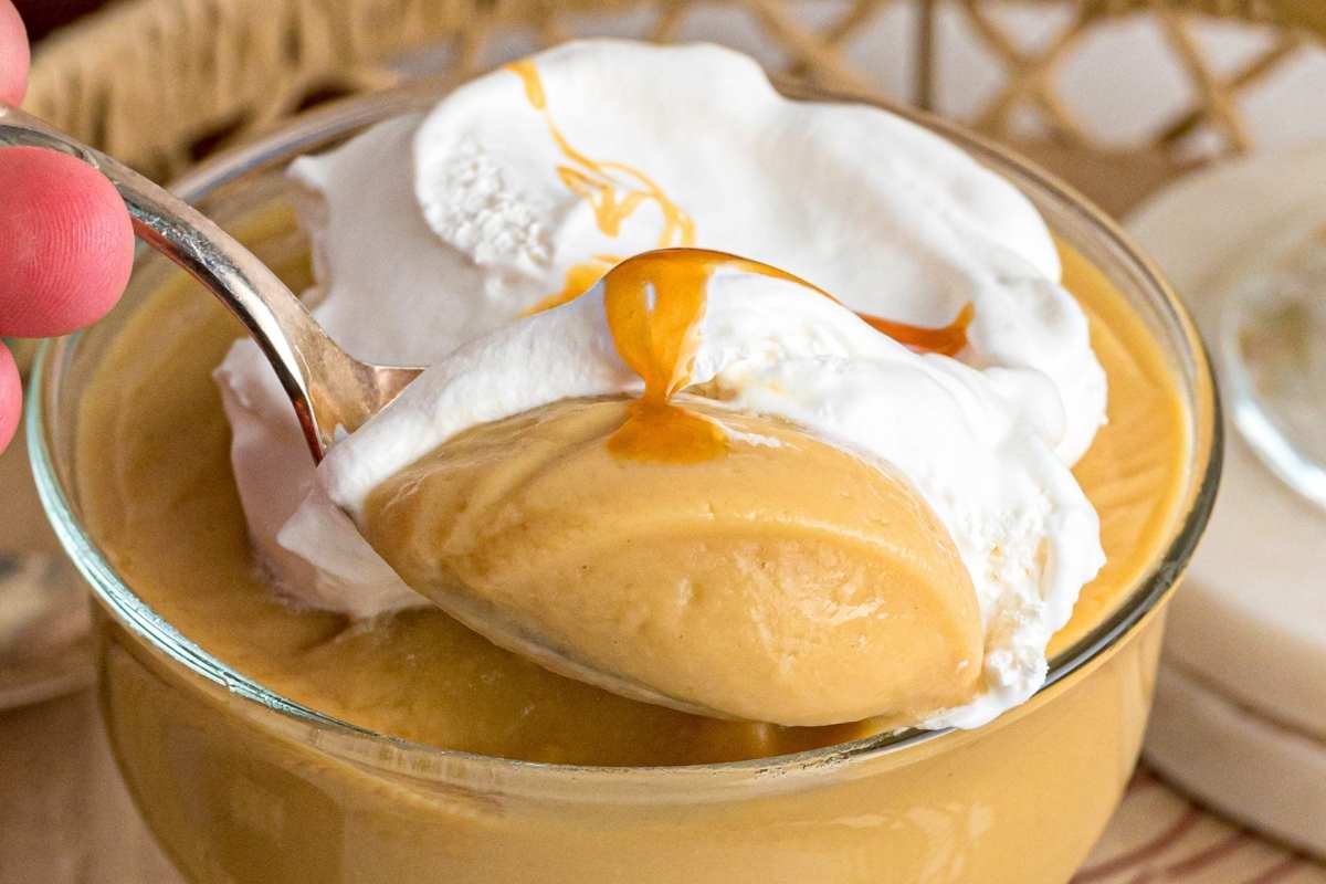 A spoonful of butterscotch pudding with whipped cream and caramel sauce.