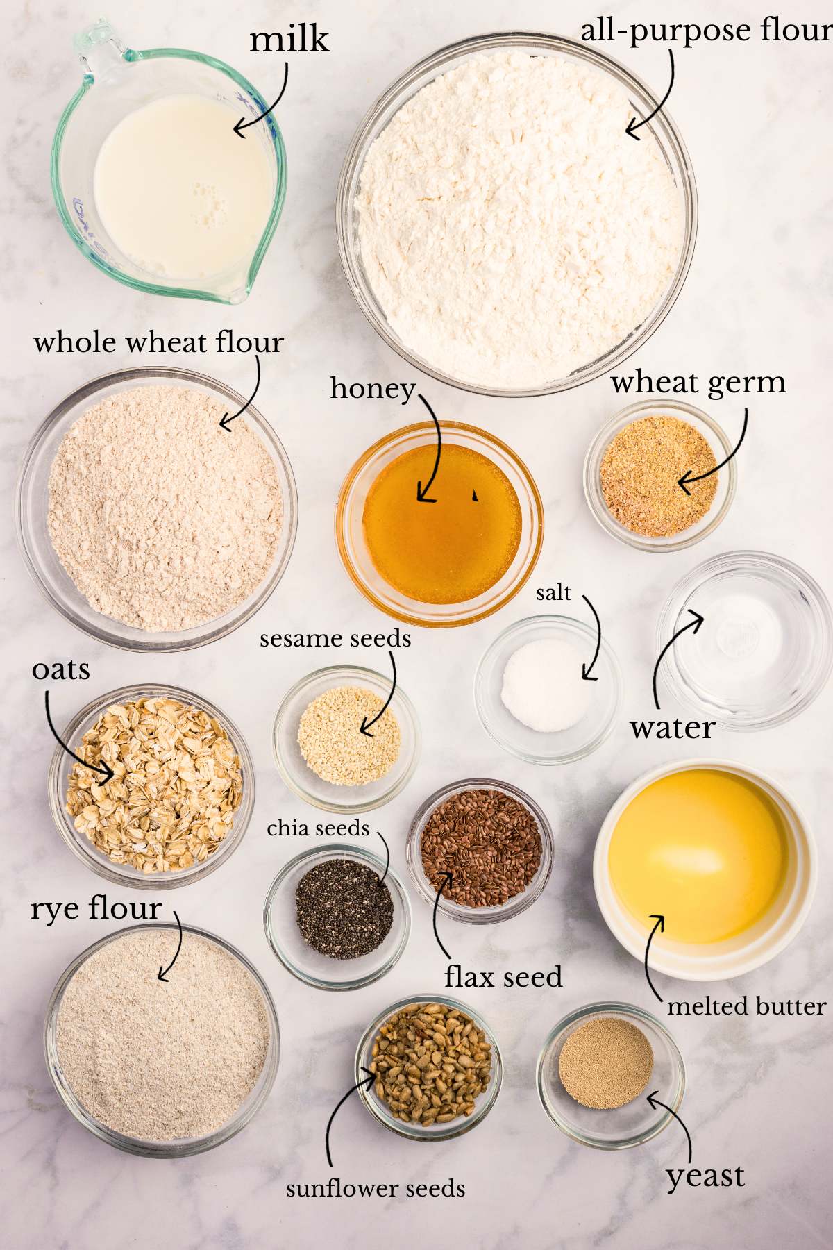 Labeled bowls with bread ingredients on a white surface.