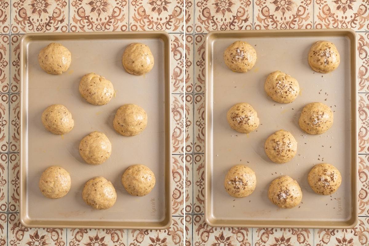 Two baking pans of risen rolls, one plain with egg wash, one topped with caraway seeds and salt.