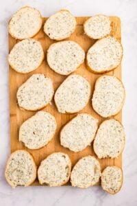 Unfrozen garlic bread sliced on cutting board