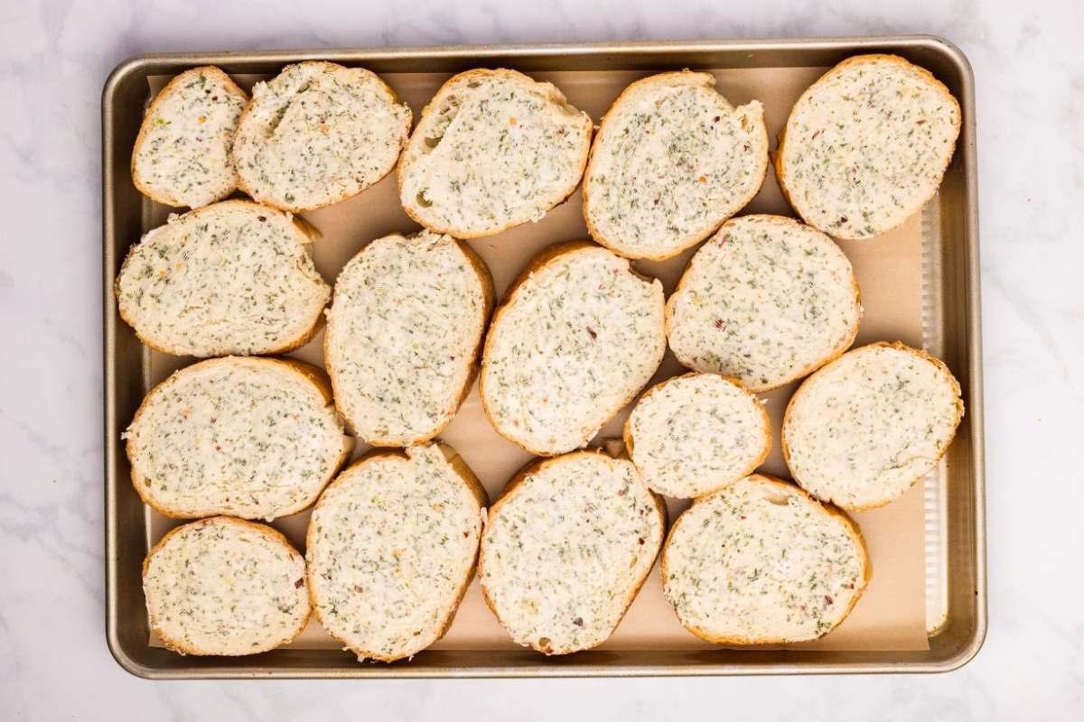 Garlic bread slices in a single layer on a baking sheet lined with parchment paper.