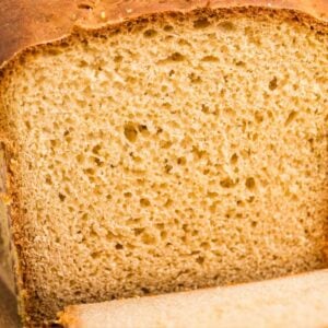 Close-up cross-section of a golden English muffin bread loaf showing airy crumb and craggy crust.