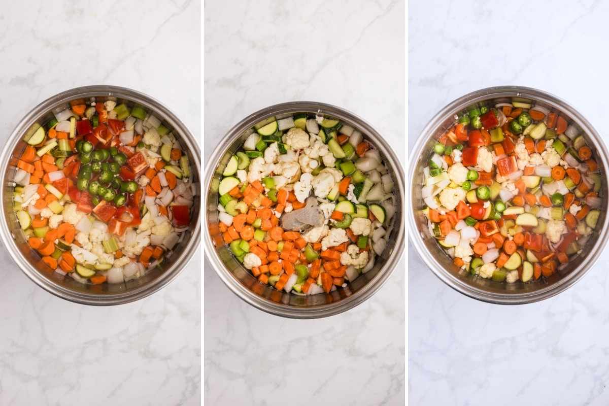 Chopped carrots, cauliflower, zucchini, peppers, and onions simmering in brine inside a stainless steel pot.