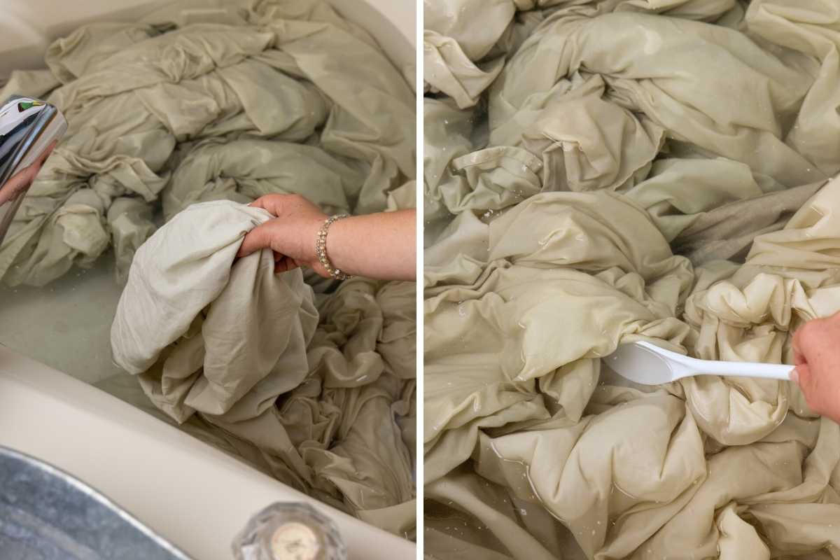 Hand submerging freshly washed beige linens into a tub of water, then stirring with a white scoop.