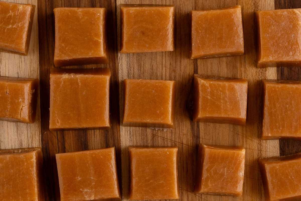 Rows of golden-amber maple caramel squares arranged on a wooden cutting board.
