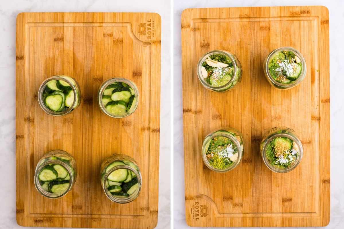 Four mason jars on a wooden cutting board packed with sliced cucumbers, dill, garlic, and pickling spices.