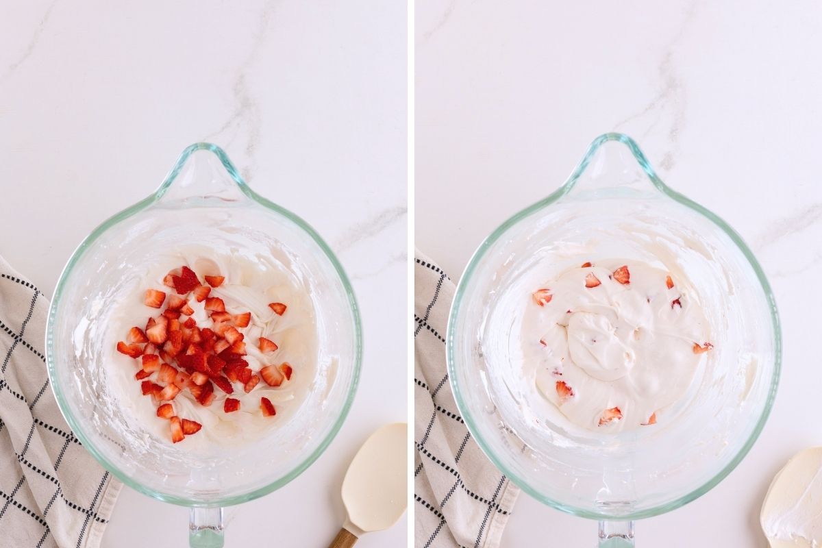 Diced strawberries being folded into whipped cream cheese filling in a glass mixing bowl.
