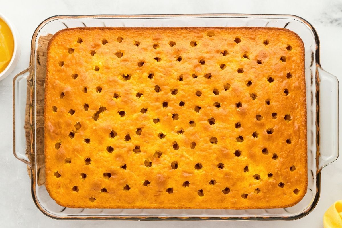 Golden lemon cake in a glass baking dish covered in rows of small poked holes.