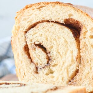Close-up cross-section of a sourdough loaf revealing a dark cinnamon swirl through soft golden crumb.
