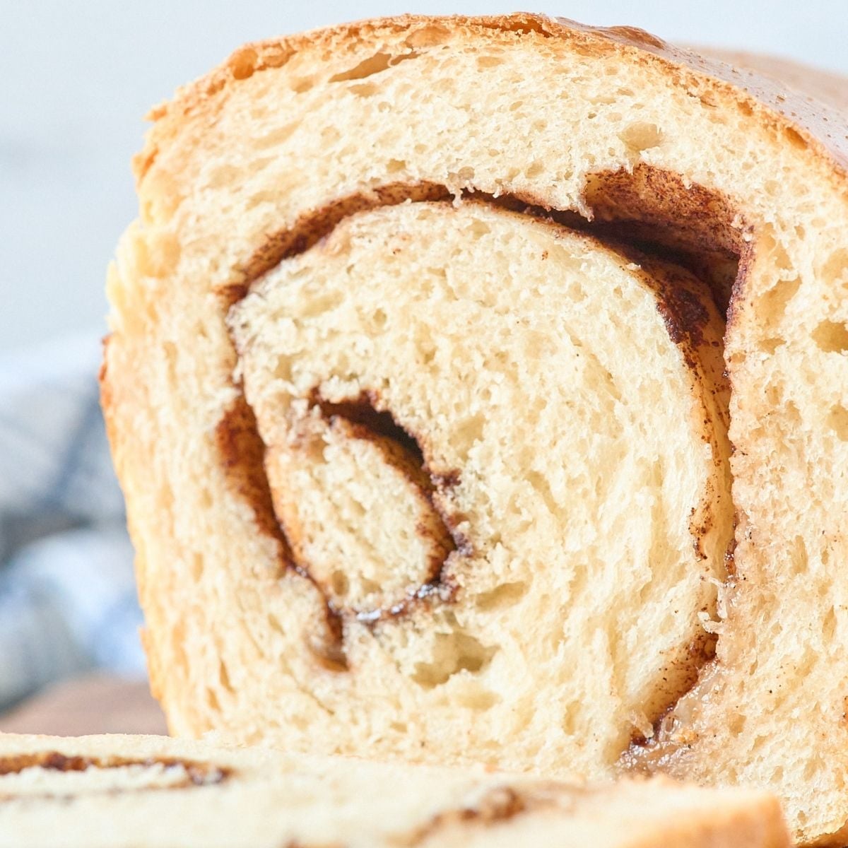 Close-up cross-section of a sourdough loaf revealing a dark cinnamon swirl through soft golden crumb.