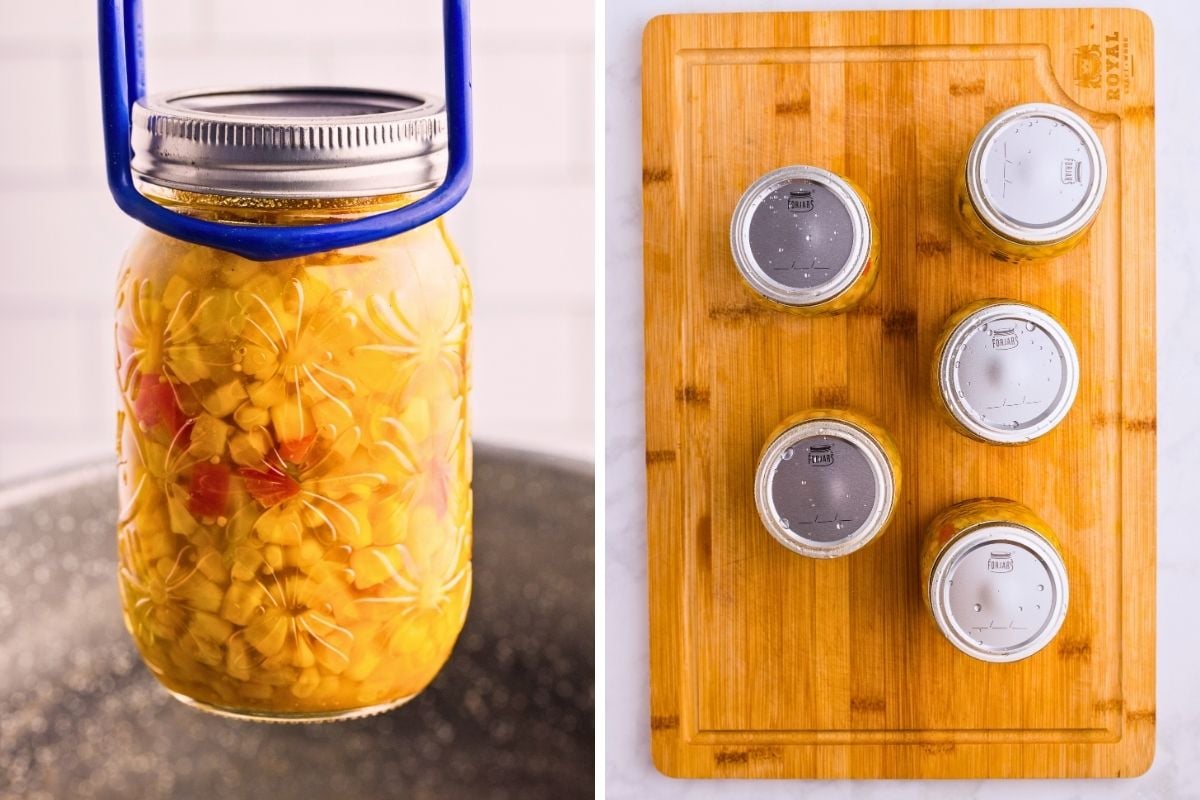 Jar of corn relish lifted from canner and finished jars cooling on a wooden cutting board.