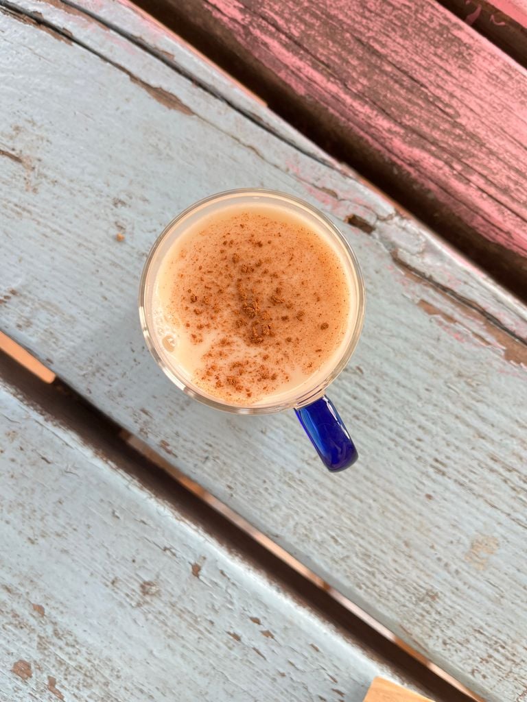 Warm chai latte with cinnamon in blue mug on rustic wooden table.
