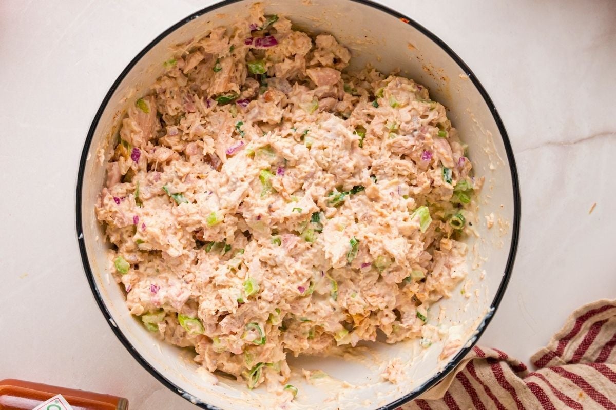 Shredded smoked chicken tossed with mayonnaise, red onion, and celery in a white bowl.