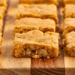 Golden butterscotch bars cut into squares and arranged in rows on a wooden cutting board.