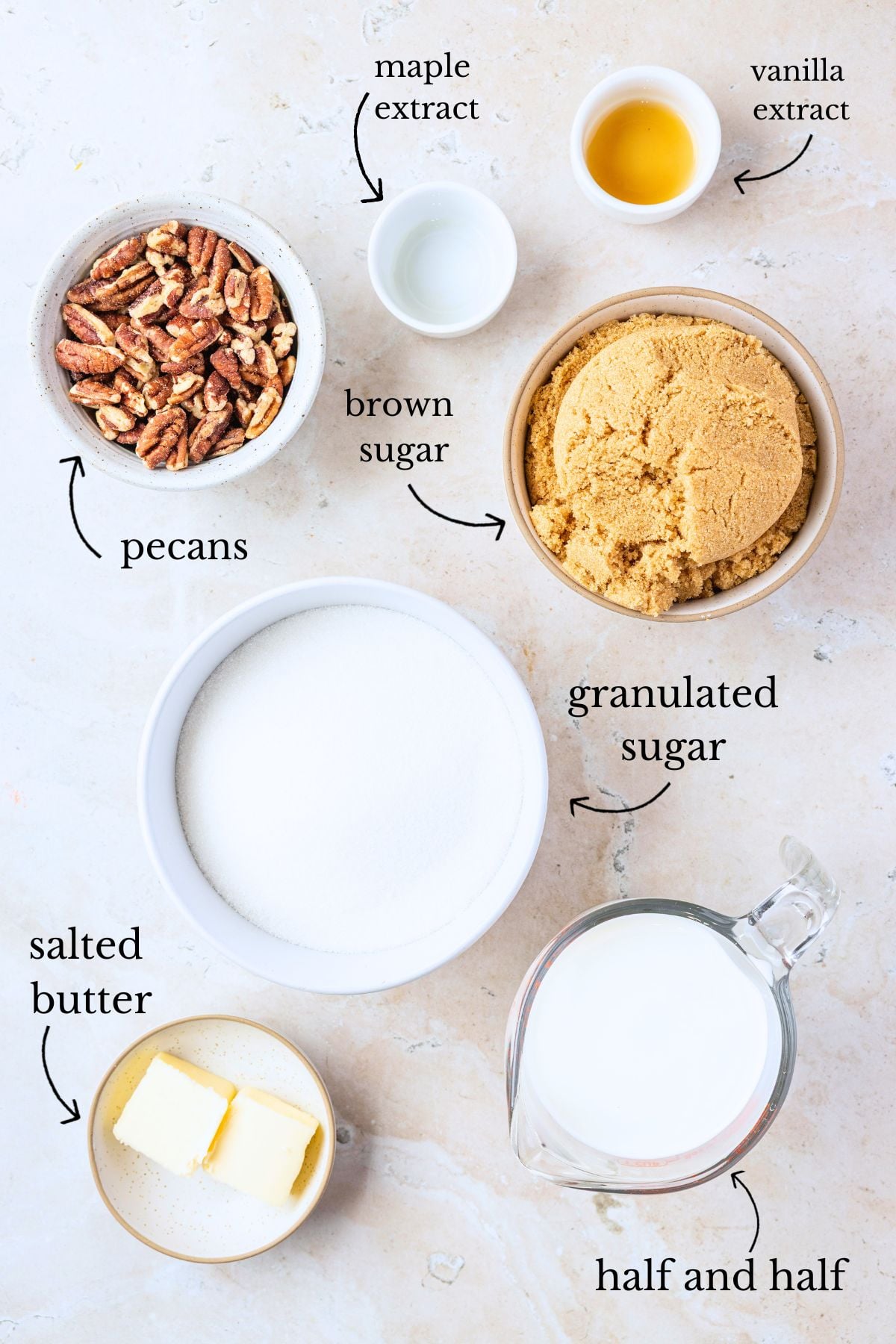 Labeled bowls of pecans, brown sugar, granulated sugar, butter, half and half, maple and vanilla extracts on stone.