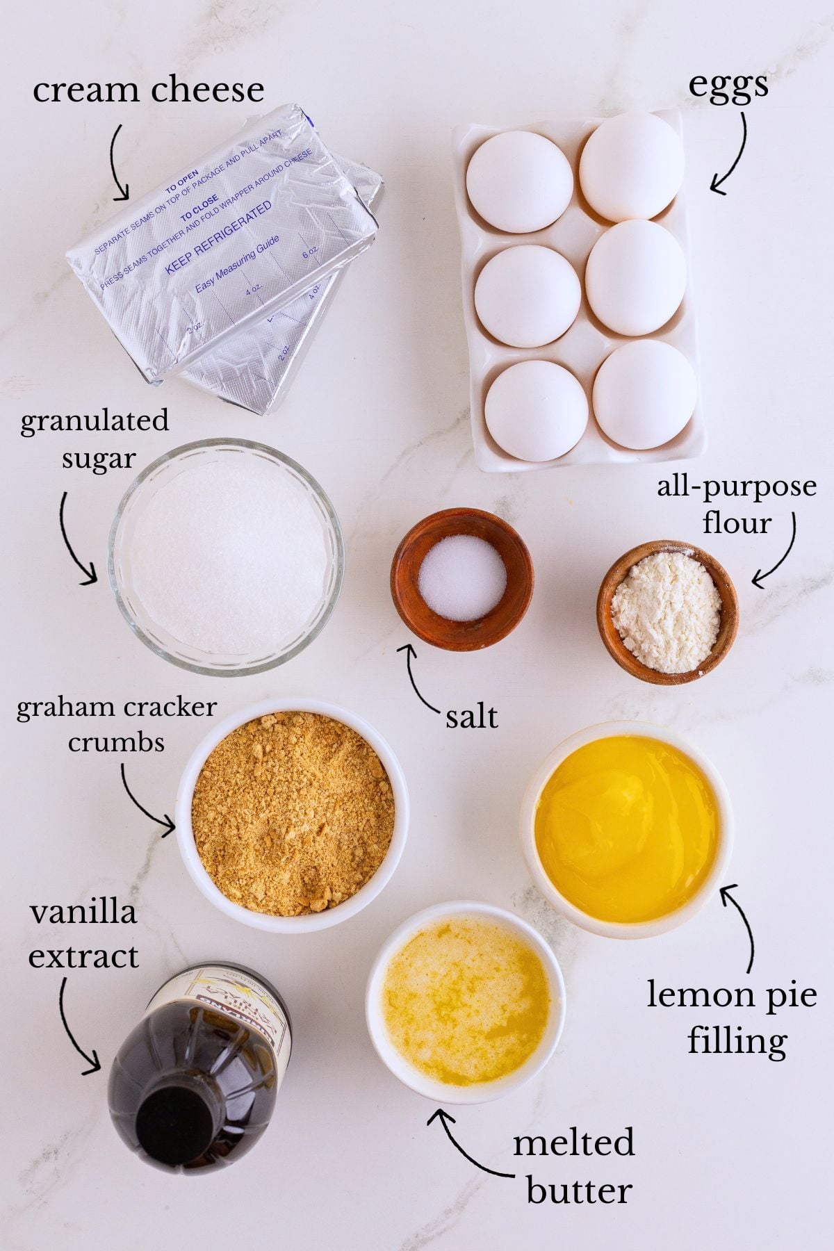 Labeled ingredients for lemon cheesecake bars including cream cheese, eggs, sugar, graham crumbs, lemon filling, butter, flour, salt, and vanilla.