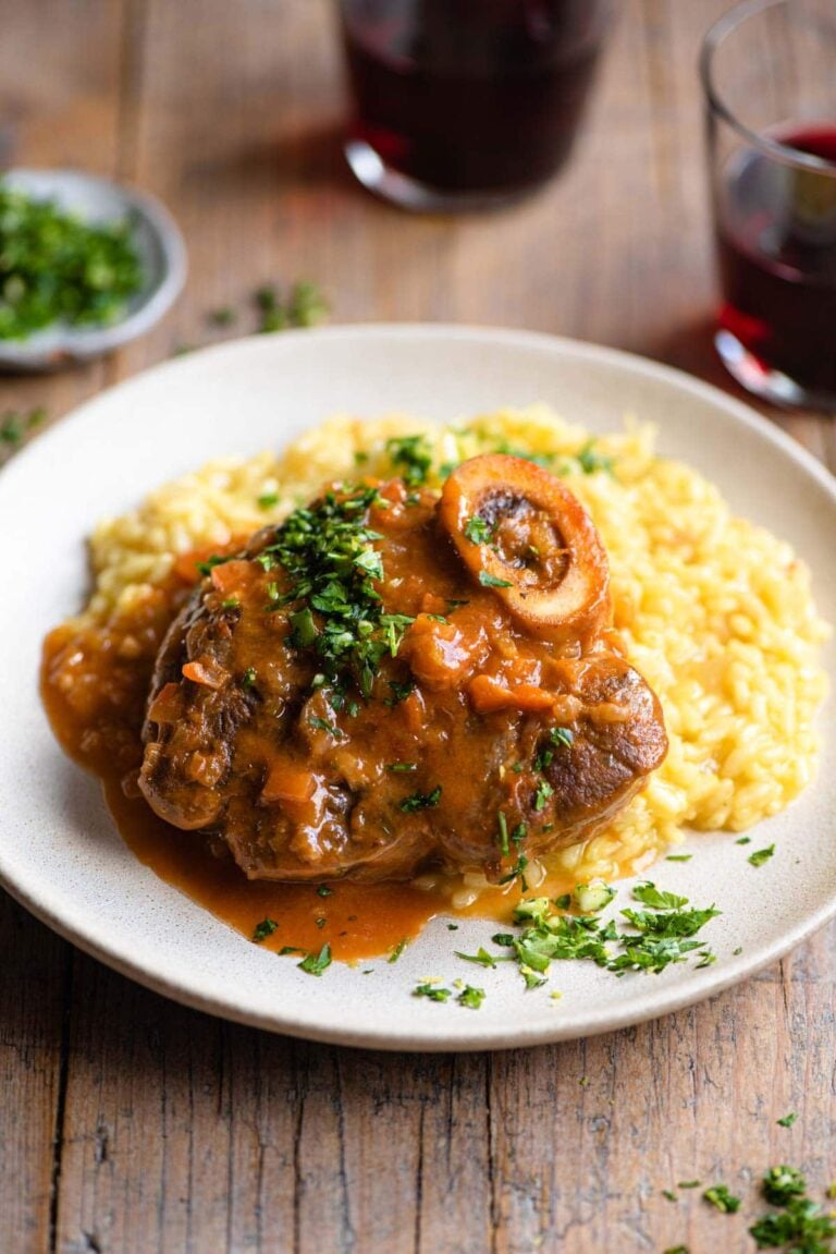 osso bucco smothered with sauce on a plate with mashed vegetables